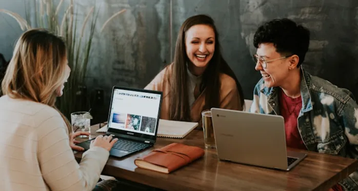 Three colleagues reviewing a Shopify storefront together on laptops