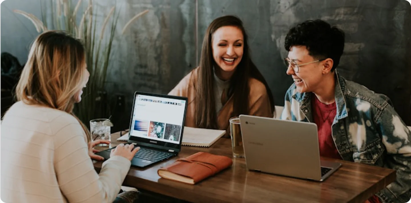 Three colleagues reviewing a Shopify storefront together on laptops