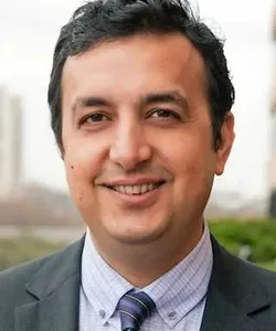 Amit Malhotra, CTO of buybuy BABY, smiling in a grey suit jacket and checked shirt.